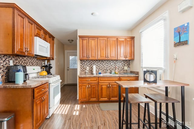 kitchen featuring backsplash, white appliances, light hardwood / wood-style flooring, and sink