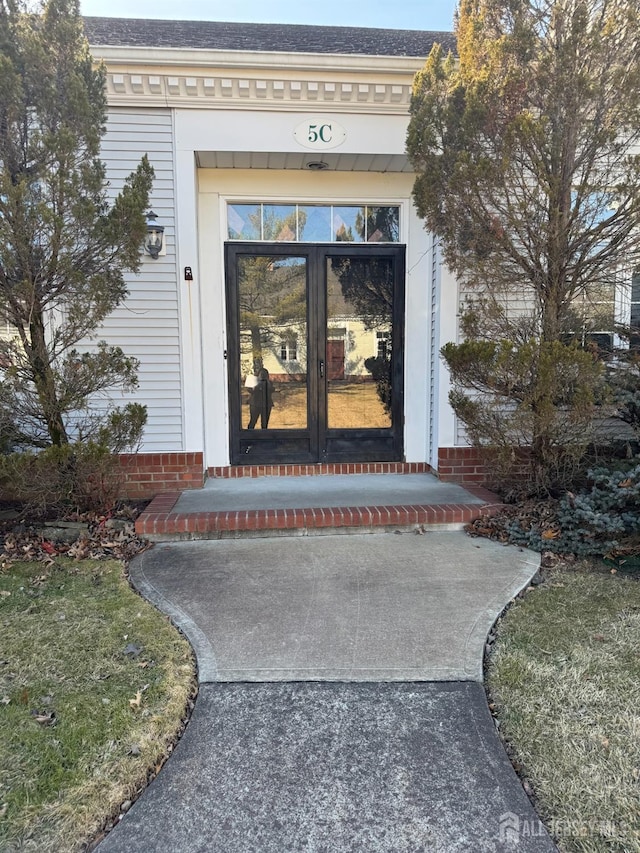 entrance to property featuring roof with shingles