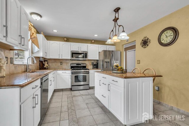 6 Muravski Ct, South River, NJ 08882 - kitchen with stainless steel appliances, decorative backsplash, light tile patterned floors, white cabinets, and decorative light fixtures