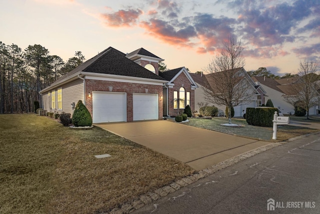 view of front of property with a garage, a yard, brick siding, and driveway