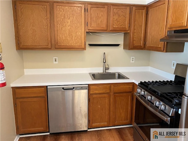 kitchen featuring under cabinet range hood, appliances with stainless steel finishes, light countertops, and a sink