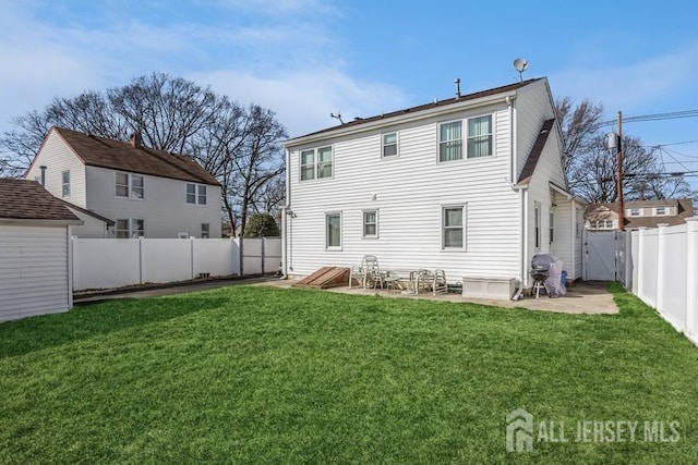 rear view of house featuring a lawn, a patio, and a fenced backyard