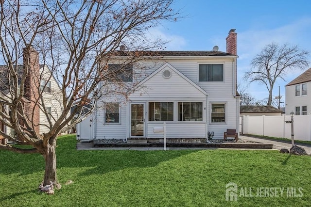 rear view of house featuring a yard, fence, and a chimney