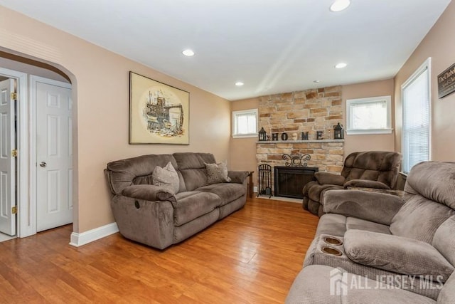 living area with arched walkways, light wood-style floors, and a healthy amount of sunlight