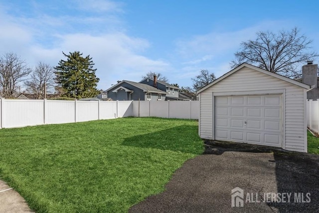 view of yard with a detached garage, an outdoor structure, driveway, and fence