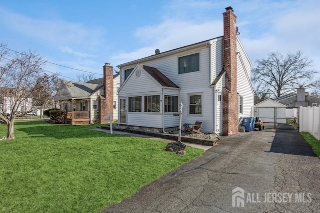 view of front of property with a garage, a chimney, a front lawn, and an outdoor structure