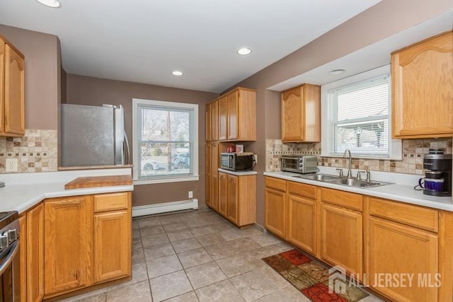 kitchen featuring light countertops, baseboard heating, appliances with stainless steel finishes, and a sink