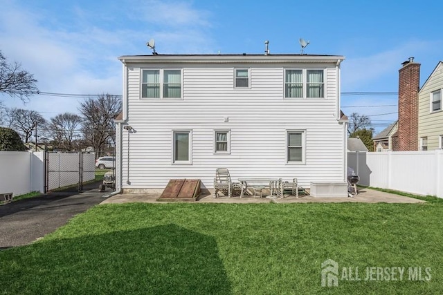 back of house with a yard, a fenced backyard, and a gate