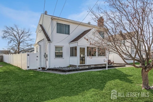 rear view of property featuring a gate, a lawn, a chimney, and fence