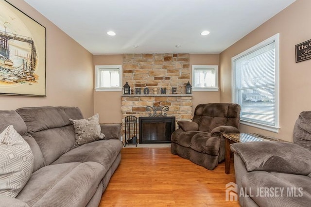 living room featuring recessed lighting, light wood-style flooring, and a fireplace