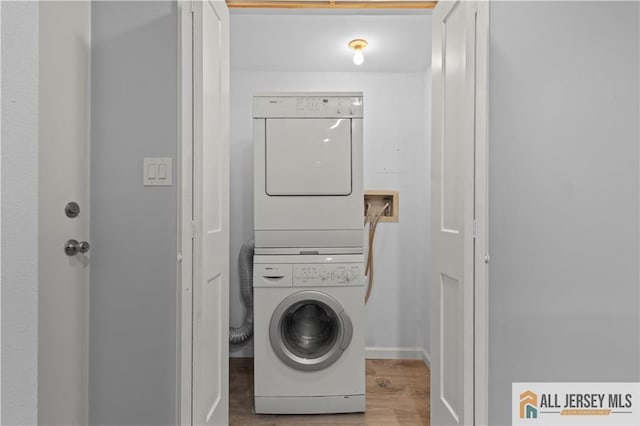 laundry area with hardwood / wood-style floors and stacked washing maching and dryer