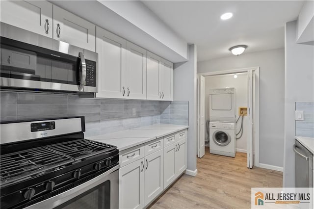 kitchen with stainless steel appliances, white cabinetry, tasteful backsplash, and stacked washer and dryer