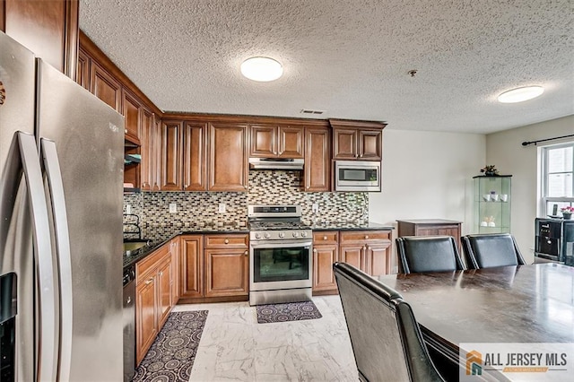 32 Prestwick Way Unit 32, Edison, NJ 08820 - kitchen featuring stainless steel appliances, under cabinet range hood, light marble finish floors, dark countertops, and decorative backsplash