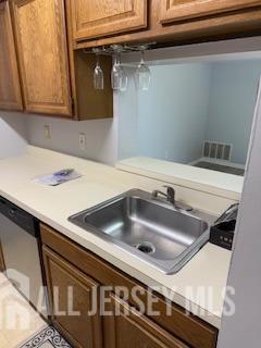 2112 Ravens Crest Dr, Plainsboro, NJ 08536 - kitchen with light countertops, stainless steel dishwasher, brown cabinetry, and a sink
