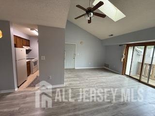 2112 Ravens Crest Dr, Plainsboro, NJ 08536 - unfurnished living room with baseboards, a ceiling fan, a skylight, and high vaulted ceiling