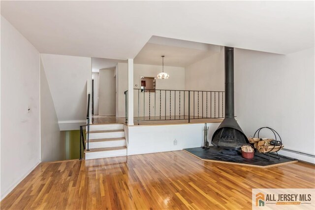 323 Gills Ln Unit 9C, Iselin, NJ 08830 - unfurnished living room featuring hardwood / wood-style floors, a chandelier, stairway, and a wood stove