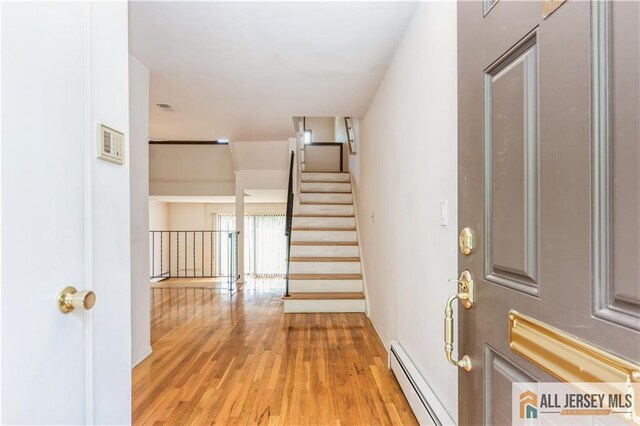 323 Gills Ln Unit 9C, Iselin, NJ 08830 - foyer entrance featuring baseboard heating, light wood-style flooring, stairs, and baseboards