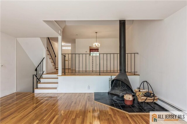 323 Gills Ln Unit 9C, Iselin, NJ 08830 - unfurnished living room with wood finished floors, a wood stove, stairs, and a chandelier