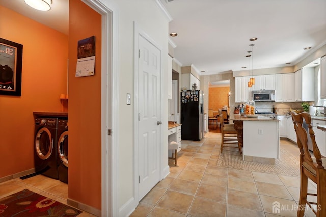 kitchen with hanging light fixtures, washing machine and dryer, appliances with stainless steel finishes, a kitchen island, and a kitchen bar