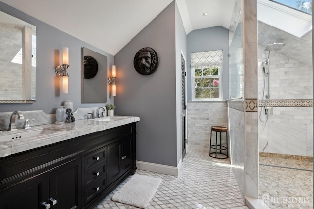 bathroom featuring tiled shower, vanity, vaulted ceiling, and tile patterned floors