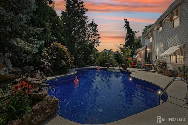 pool at dusk featuring a patio