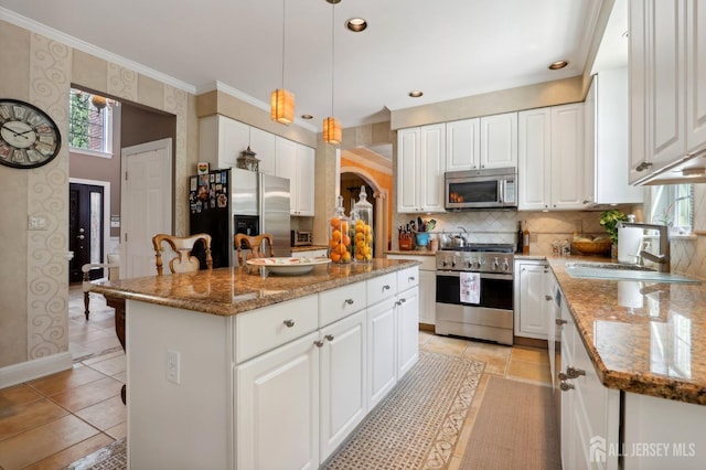 kitchen with hanging light fixtures, a center island, white cabinets, and stainless steel appliances