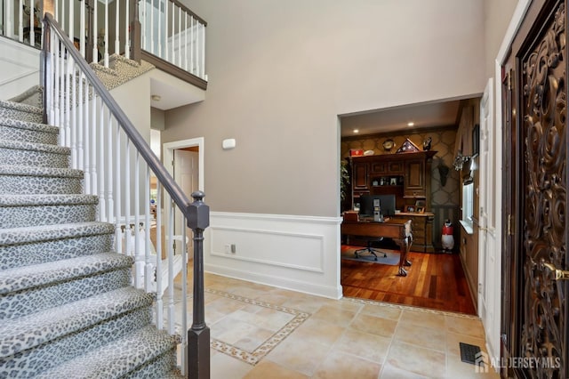 foyer entrance with crown molding, light hardwood / wood-style floors, and a high ceiling