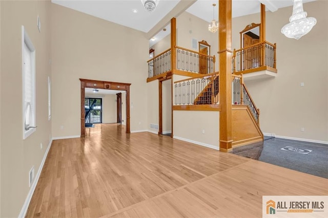 10 Signal Ct, South Brunswick, NJ 08810 - unfurnished living room with a chandelier, a towering ceiling, wood finished floors, and baseboards