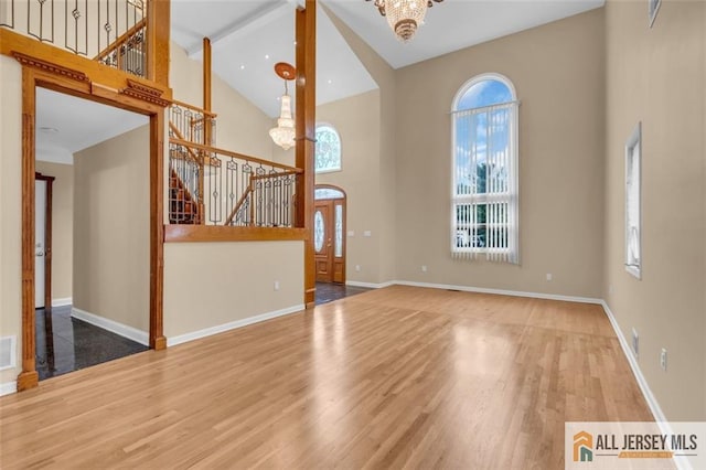 10 Signal Ct, South Brunswick, NJ 08810 - unfurnished living room featuring high vaulted ceiling, stairway, a chandelier, wood finished floors, and baseboards