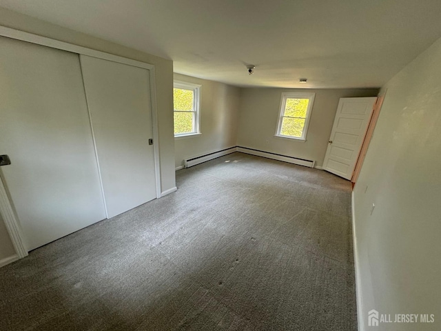 unfurnished bedroom featuring a closet, carpet floors, and a baseboard heating unit