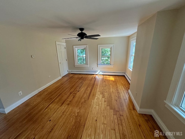 empty room with a baseboard heating unit, ceiling fan, and light hardwood / wood-style floors