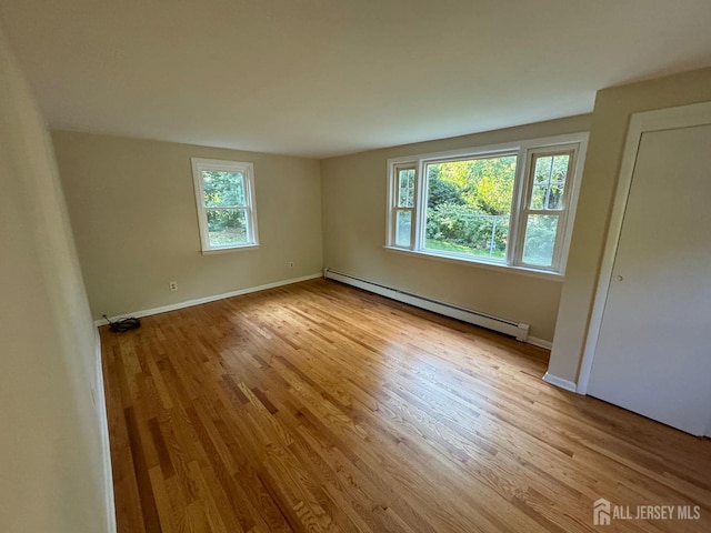 empty room featuring baseboard heating and light wood-type flooring