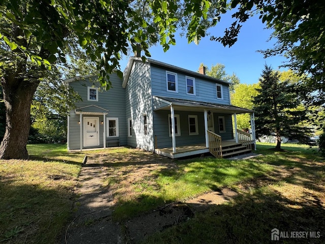 back of house with covered porch and a lawn