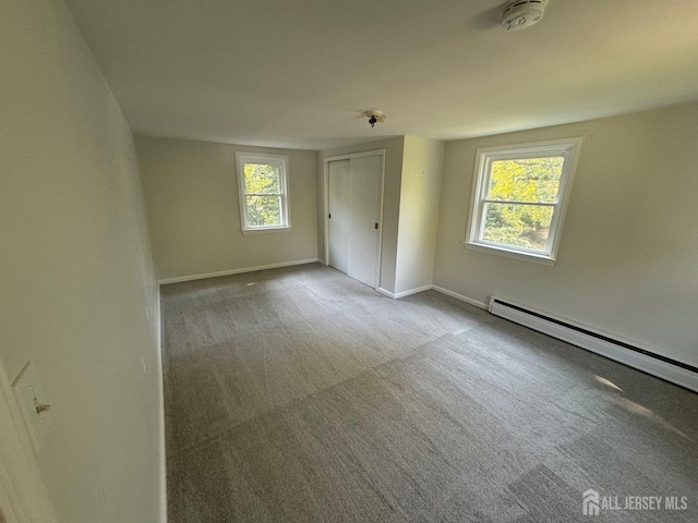 empty room featuring a baseboard radiator, a wealth of natural light, and carpet