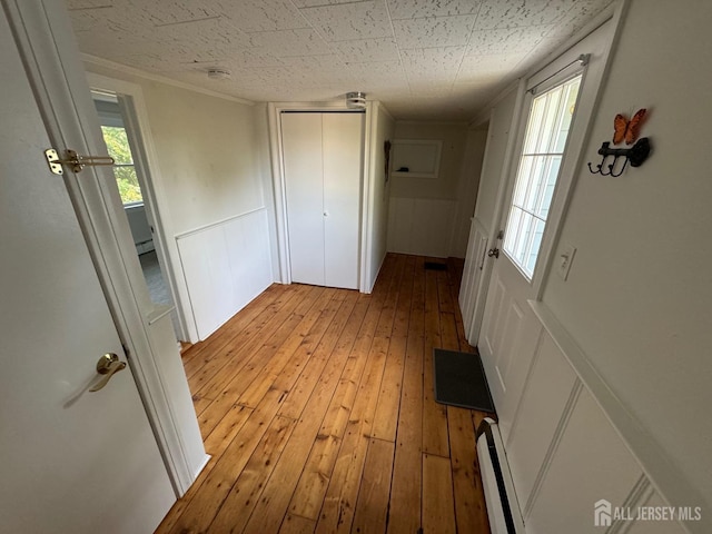 corridor with baseboard heating and light hardwood / wood-style flooring