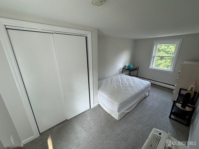 carpeted bedroom with a baseboard heating unit and a closet