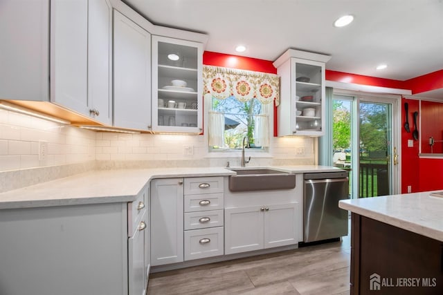 kitchen with dishwasher, a sink, decorative backsplash, glass insert cabinets, and recessed lighting