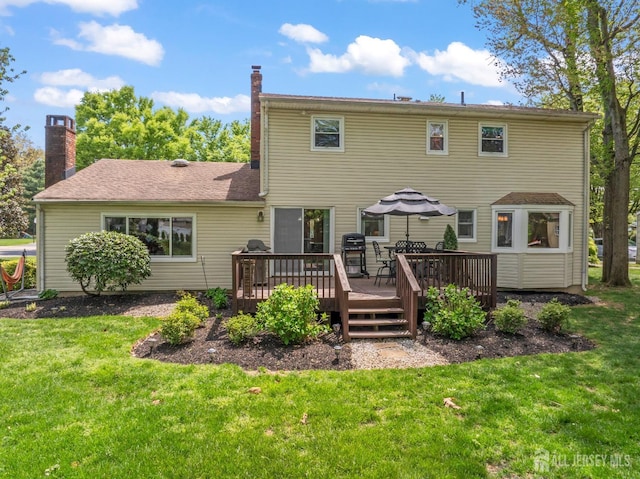rear view of property featuring a yard, a deck, and a chimney