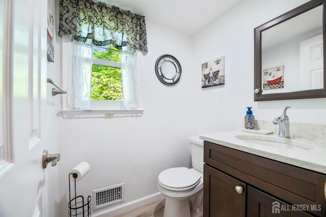 half bathroom featuring toilet, vanity, and baseboards
