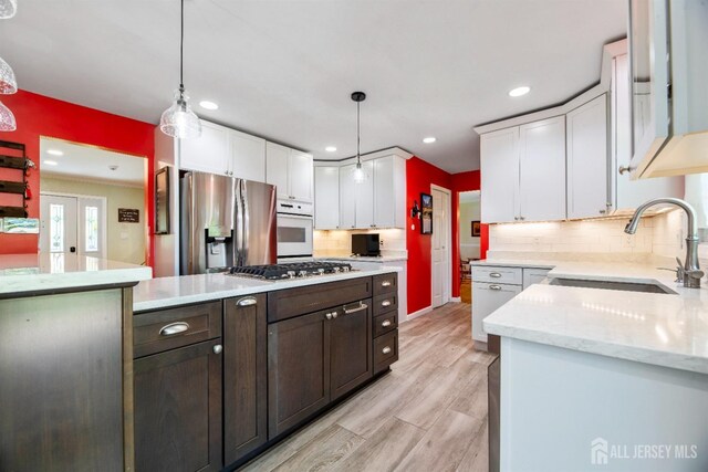 kitchen with a sink, stainless steel appliances, white cabinets, dark brown cabinets, and decorative backsplash
