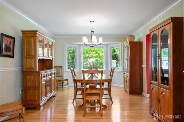 dining room featuring a chandelier, light wood-type flooring, crown molding, and baseboards