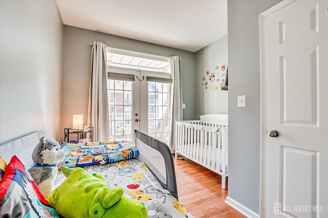 bedroom featuring wood finished floors, french doors, access to outside, and baseboards