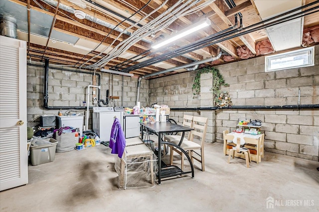 basement featuring washing machine and clothes dryer and concrete block wall