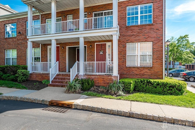 multi unit property featuring a porch and brick siding