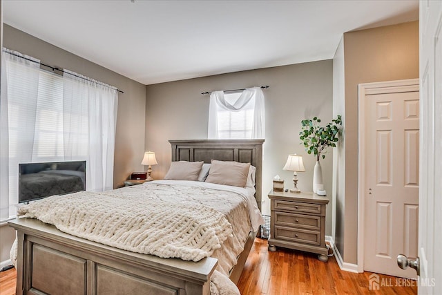 bedroom with light wood finished floors and baseboards