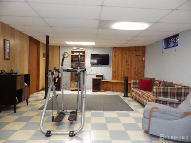 workout area featuring light floors, wooden walls, and a drop ceiling