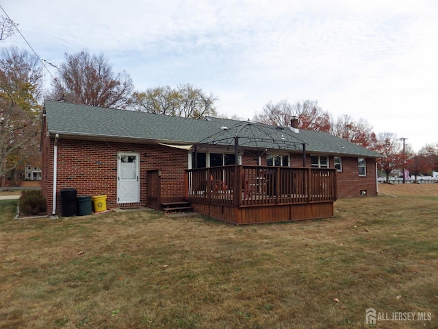 rear view of house featuring a yard, a gazebo, a wooden deck, and brick siding