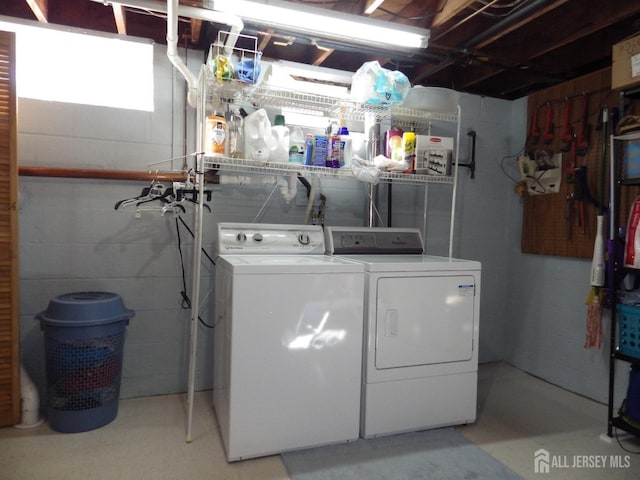 laundry area with concrete block wall and washer and clothes dryer