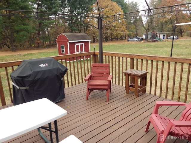 deck with an outbuilding, a playground, a yard, grilling area, and a shed