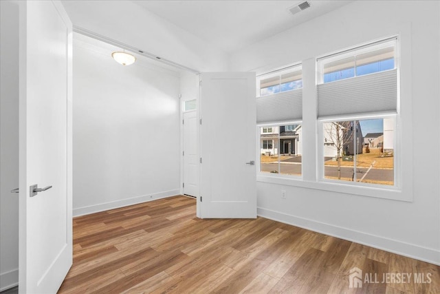 empty room featuring baseboards, visible vents, and wood finished floors